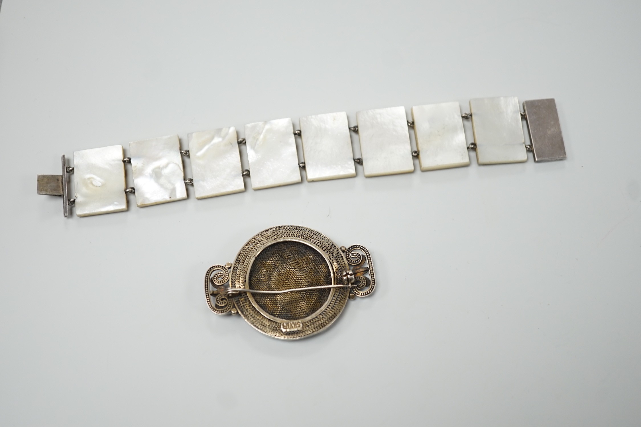 A Persian lacquered mother of pearl panel bracelet, 17cm and a Chinese filigree white metal and 'kingfisher' enamelled brooch, 54mm.